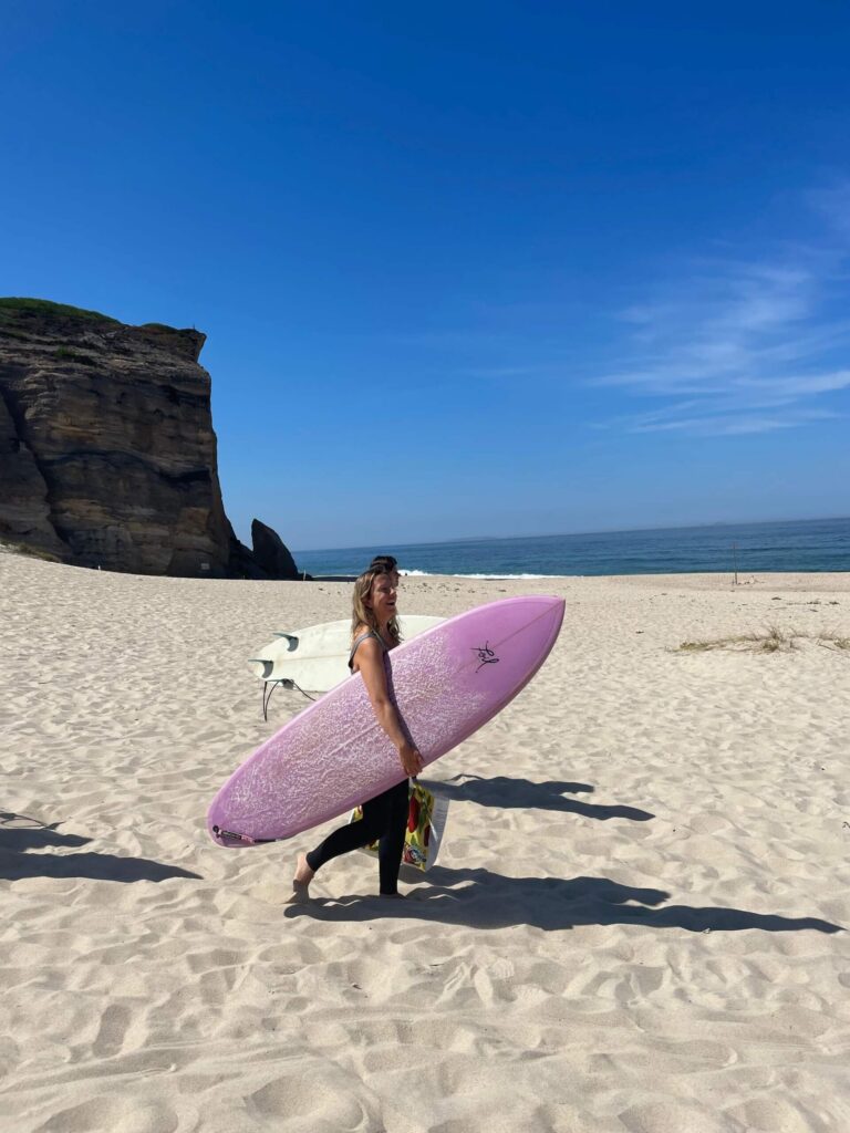 Surferka z deską na plaży - wyjazd Surf Stories