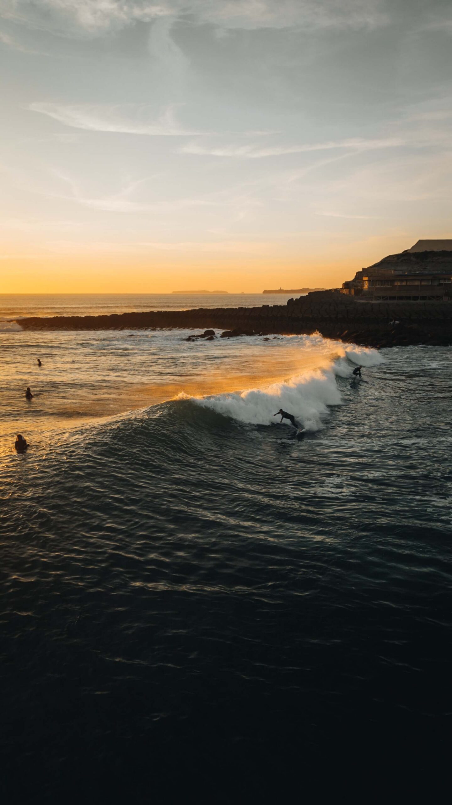 Surfers catching waves at sunset